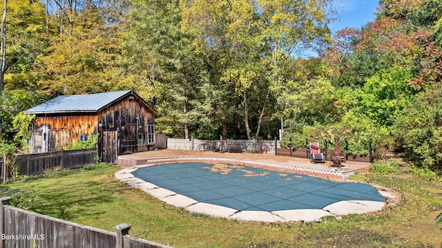 view of swimming pool featuring a lawn, a patio area, and an outbuilding