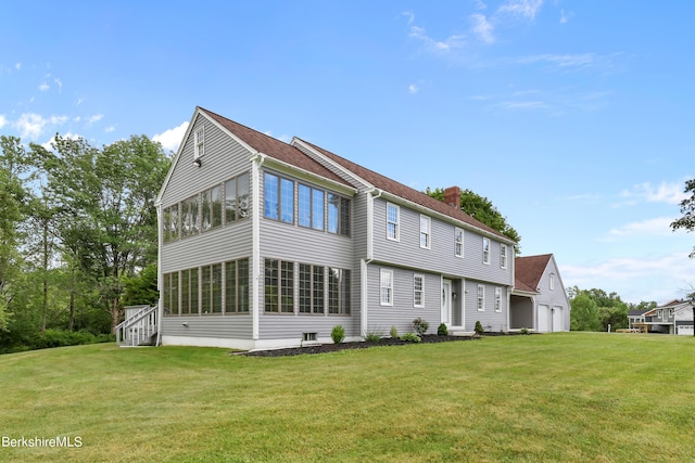 back of property with a sunroom, a garage, and a lawn