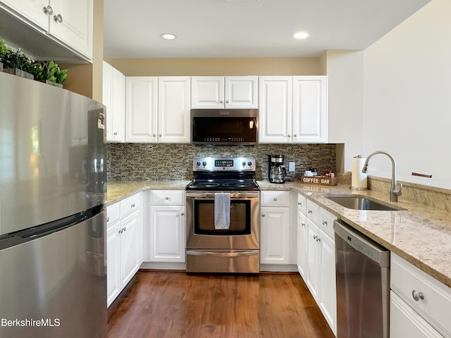 kitchen with light stone counters, stainless steel appliances, white cabinetry, and sink