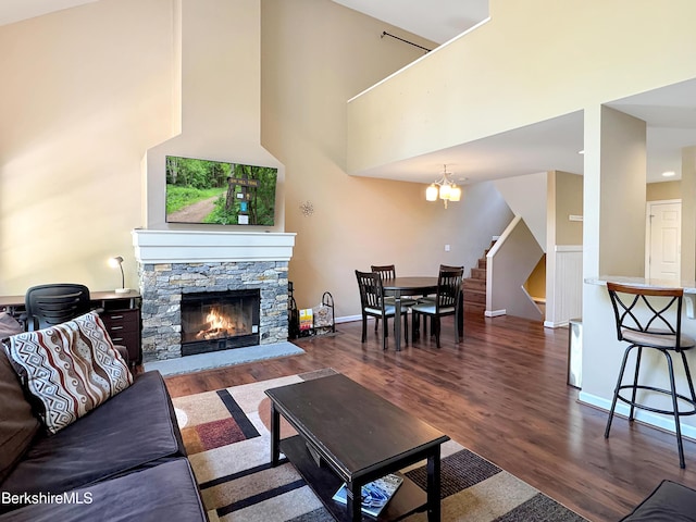 living room featuring a fireplace, a towering ceiling, dark hardwood / wood-style floors, and a notable chandelier