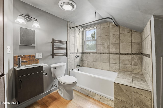 bathroom featuring vanity, toilet, vaulted ceiling, wood finished floors, and  shower combination
