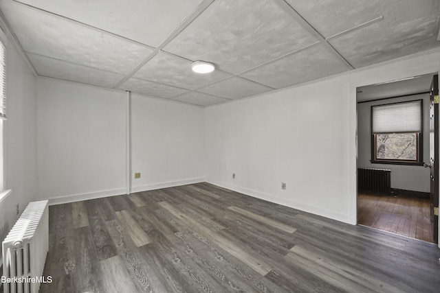 spare room with radiator heating unit, wood finished floors, and baseboards
