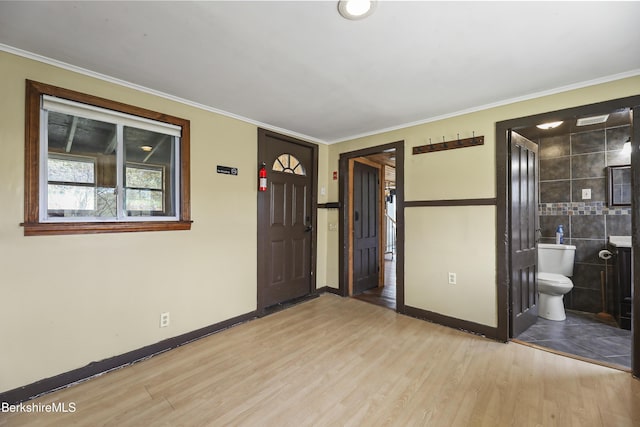 foyer entrance featuring crown molding, wood finished floors, and baseboards