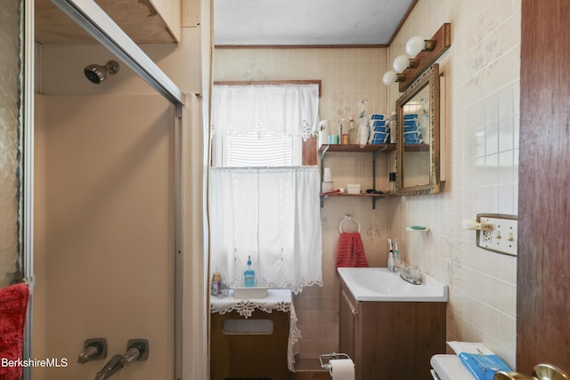 bathroom featuring vanity, tile walls, a shower with door, and toilet
