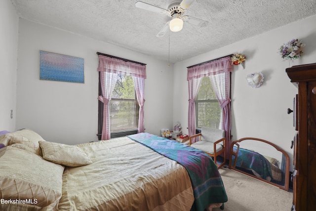 bedroom with ceiling fan, carpet floors, multiple windows, and a textured ceiling