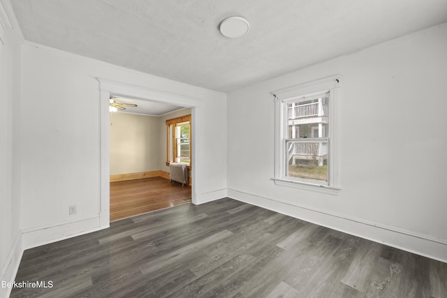 unfurnished room with baseboards, ornamental molding, radiator, and dark wood-type flooring