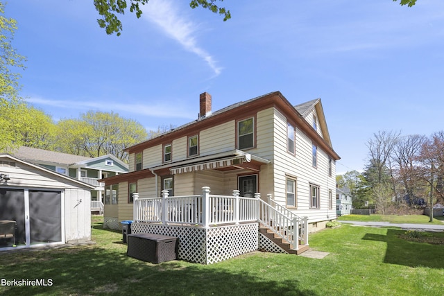 rear view of property featuring a lawn, an outdoor structure, a storage shed, and a chimney