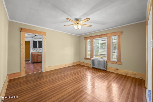 unfurnished room featuring baseboards, ceiling fan, radiator heating unit, and wood finished floors
