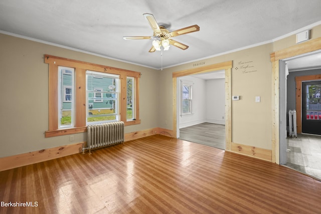unfurnished room with a ceiling fan, ornamental molding, radiator heating unit, and wood finished floors
