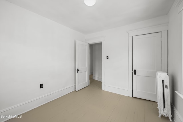 unfurnished bedroom with radiator, baseboards, a closet, and light wood finished floors