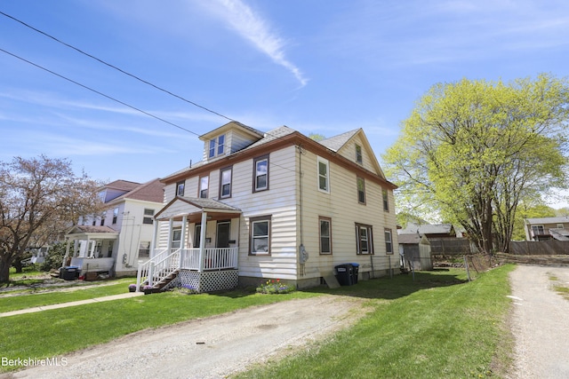 view of front of house with a front lawn, fence, and covered porch