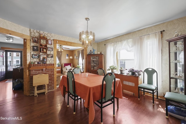 dining area with wallpapered walls, wood finished floors, and ceiling fan with notable chandelier