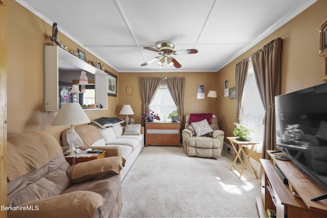 living room featuring ornamental molding, light carpet, a ceiling fan, and wallpapered walls