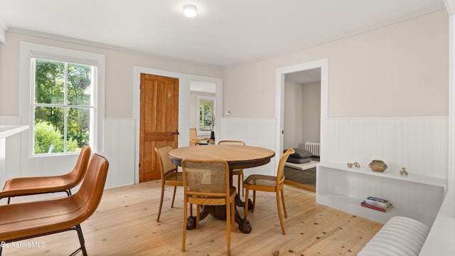 dining space featuring light hardwood / wood-style floors, radiator heating unit, and crown molding