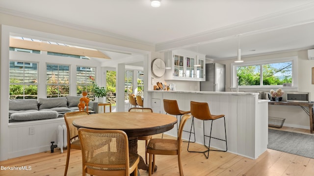 dining space with plenty of natural light, light wood-type flooring, crown molding, and a wall mounted AC