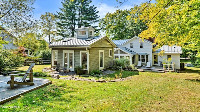 back of property featuring a deck and a lawn