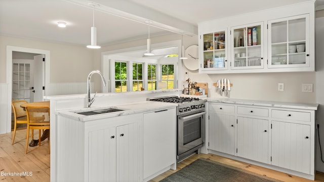 kitchen featuring high end stove, sink, hardwood / wood-style flooring, white cabinetry, and hanging light fixtures