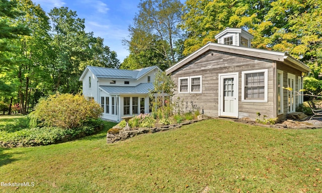 back of house with a sunroom and a yard