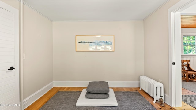 living area with crown molding, radiator heating unit, and wood-type flooring