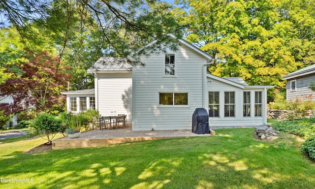 back of house featuring a patio, a sunroom, and a lawn