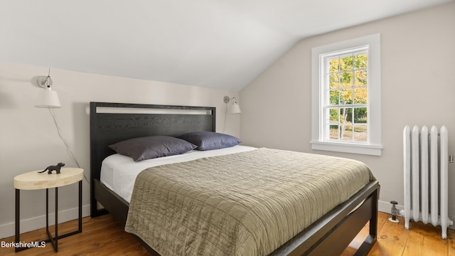 bedroom featuring radiator heating unit, vaulted ceiling, and wood-type flooring