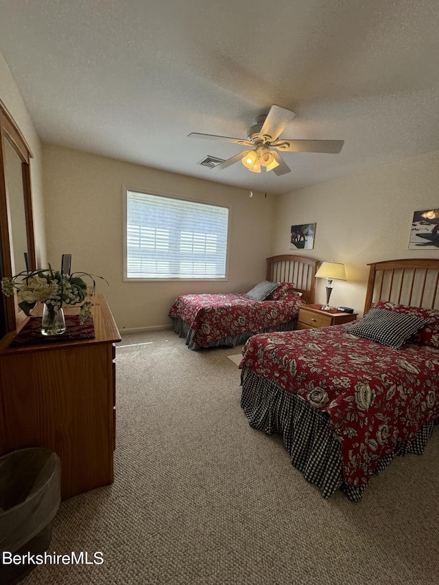 carpeted bedroom with ceiling fan and a textured ceiling