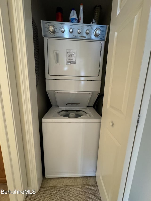 clothes washing area featuring light tile patterned floors and stacked washer / drying machine