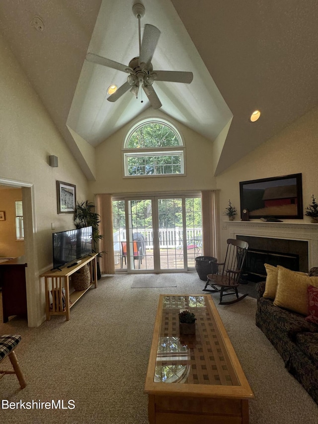 living room featuring carpet flooring, ceiling fan, and a towering ceiling