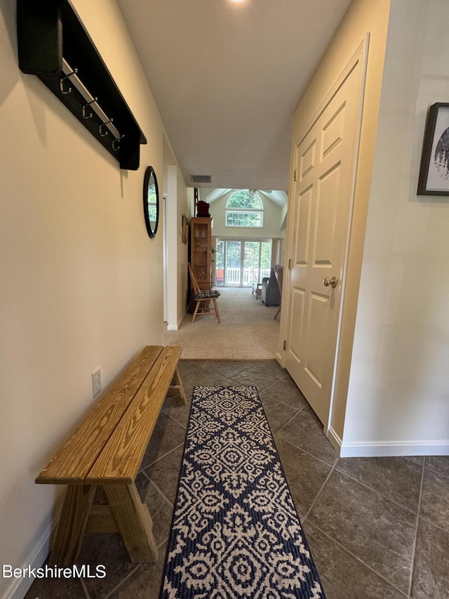 hallway featuring dark carpet and vaulted ceiling