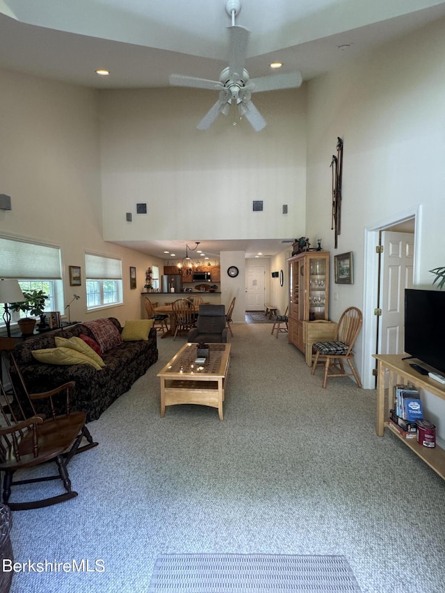 carpeted living room with a high ceiling and ceiling fan