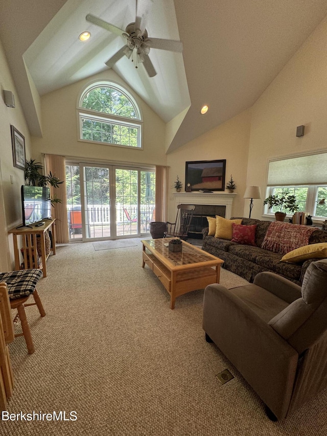 living room featuring a fireplace, light colored carpet, high vaulted ceiling, and ceiling fan