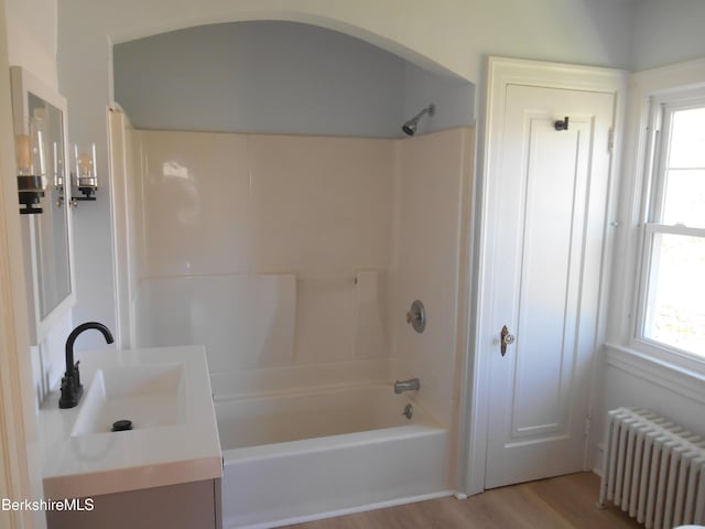 full bathroom with plenty of natural light, tub / shower combination, radiator heating unit, and wood finished floors