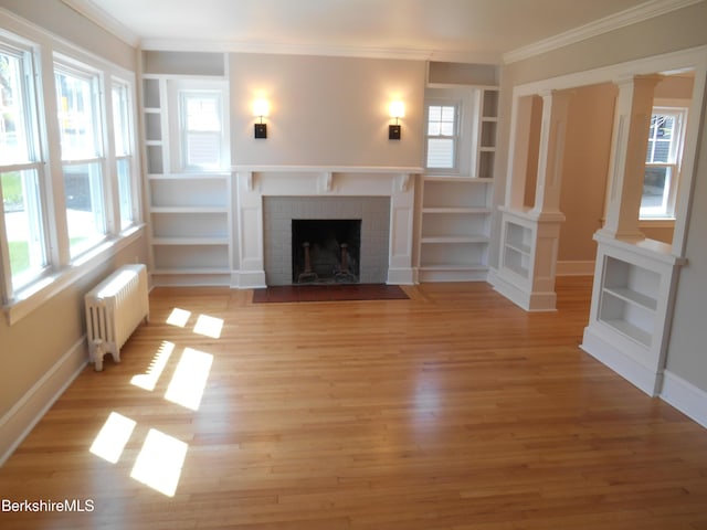 unfurnished living room with crown molding, a wealth of natural light, radiator, and a fireplace
