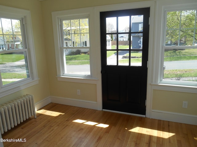 doorway with wood finished floors, baseboards, and radiator heating unit