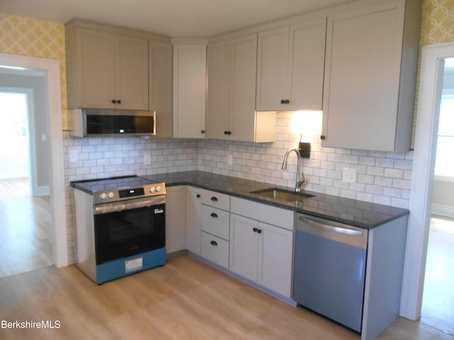 kitchen with a sink, appliances with stainless steel finishes, plenty of natural light, and light wood finished floors