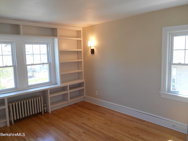 unfurnished room with baseboards, wood finished floors, and radiator
