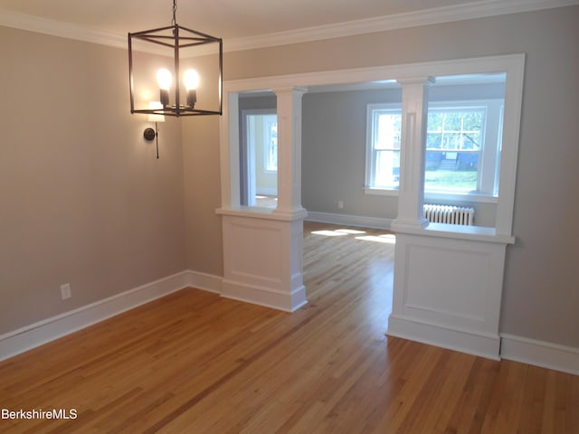 unfurnished dining area with light wood-style floors, decorative columns, baseboards, a notable chandelier, and radiator heating unit