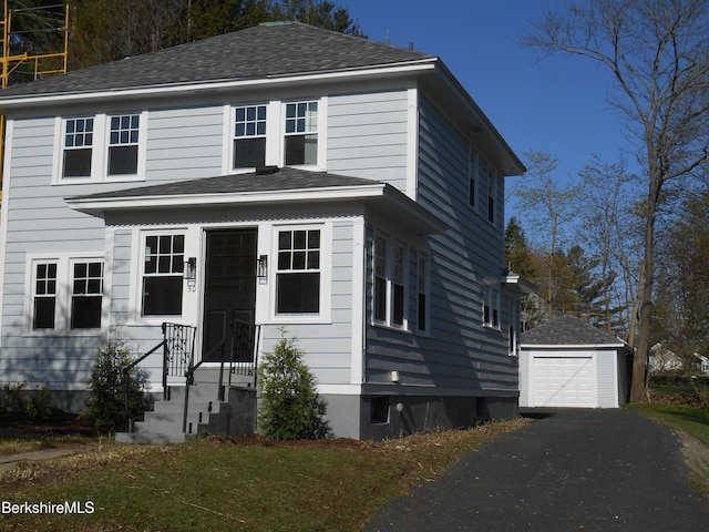 traditional-style house featuring roof with shingles, an outbuilding, driveway, and a detached garage
