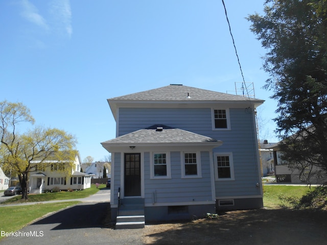 rear view of house featuring roof with shingles and entry steps
