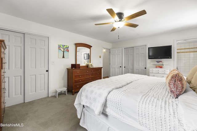 carpeted bedroom with ceiling fan and two closets