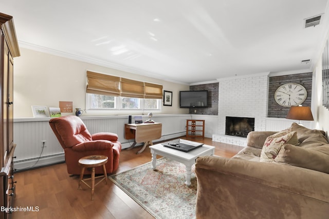 living room featuring hardwood / wood-style floors, crown molding, a fireplace, and a baseboard heating unit