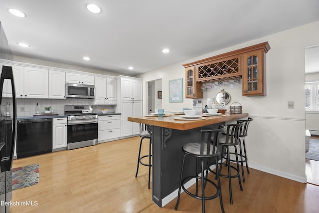 kitchen featuring white cabinets, stainless steel appliances, a breakfast bar, and kitchen peninsula