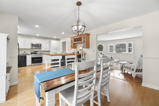 dining space featuring light wood-type flooring and an inviting chandelier