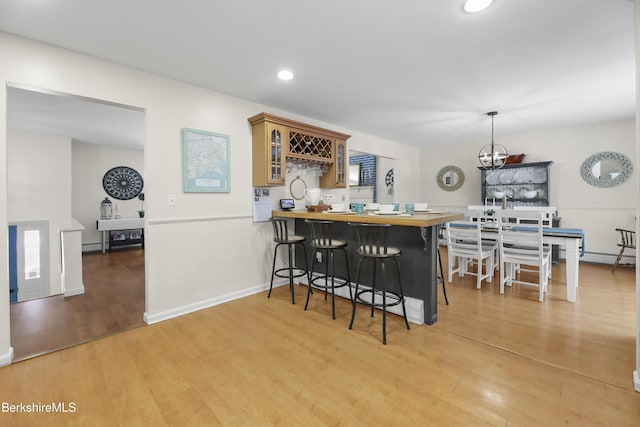 kitchen with a breakfast bar, light wood-type flooring, decorative light fixtures, and kitchen peninsula