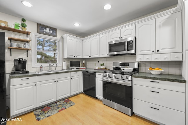 kitchen with light hardwood / wood-style floors, stainless steel appliances, sink, white cabinetry, and tasteful backsplash