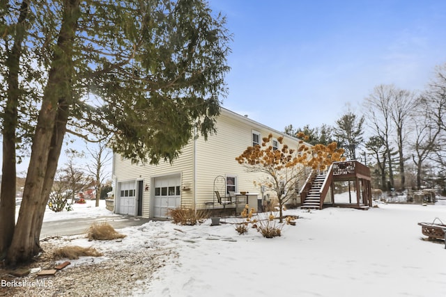 snow covered property with a deck and a garage