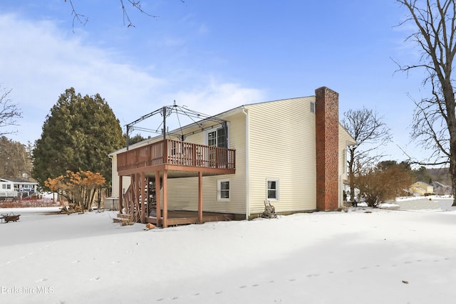 snow covered rear of property featuring a deck