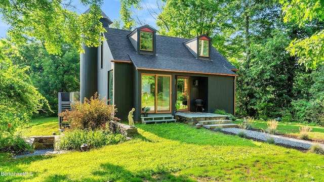 rear view of house featuring roof with shingles and a yard