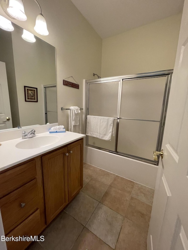 bathroom featuring tile patterned flooring, enclosed tub / shower combo, and vanity