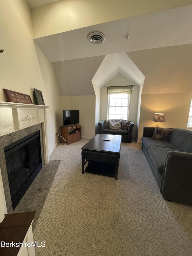 living room featuring a tile fireplace, lofted ceiling, and carpet floors